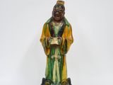 une statue verte et jaune représentant un homme tenant un livre