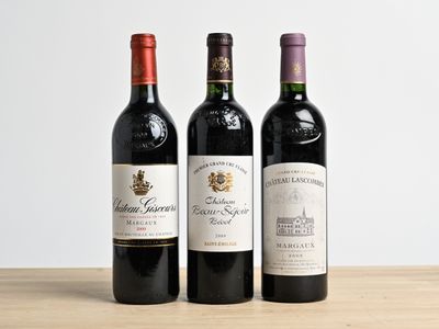 trois bouteilles de vin sont alignées sur une table en bois