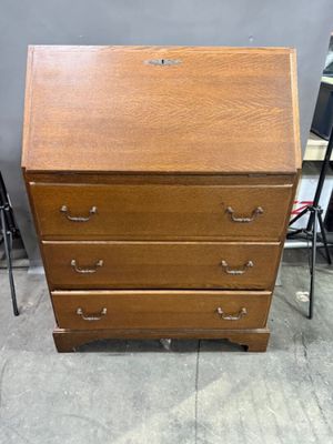 a wooden desk with drawers and a chair in front of it