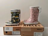 two children ' s rain boots sitting on top of boxes on a table