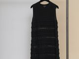 a black dress hanging on a clothes rack in a room