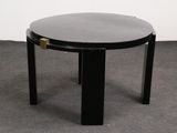 a black table with a round glass top on a carpeted floor