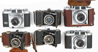 several old cameras are lined up in a row on a white surface