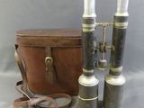 two silver and black binoculars and a brown bag on a gray surface