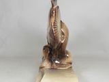 statue of a bird sitting on a book on a white surface