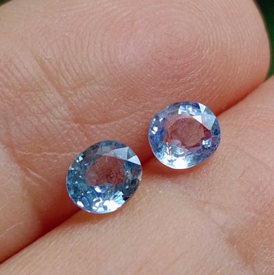 pair of blue topaz gems sitting on a person ' s finger