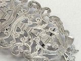 a silver brooch that is on a white surface