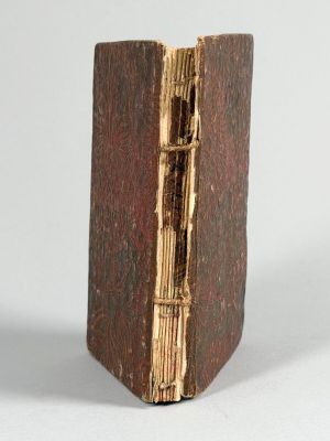un vieux livre à la couverture en bois posé sur une surface blanche
