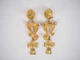 two gold earrings with seahorses and cross on them