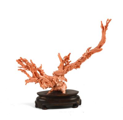une sculpture en corail orange posée sur un socle noir, elle-même posée sur une surface blanche