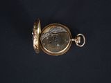 a close up of a pocket watch on a black surface