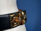 a close up of a mannequin torso wearing a black belt with gold buckles