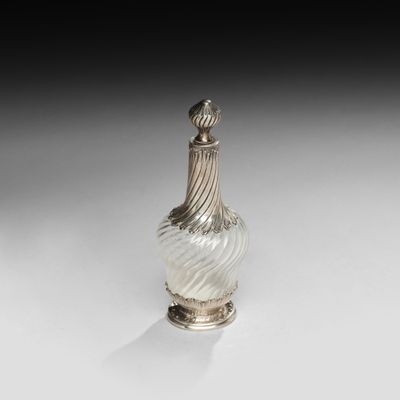 un vase en argent et en verre posé sur un socle, sur une surface blanche