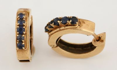 une paire de boucles d'oreilles créoles en or et saphir bleu sur fond blanc