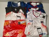 Plusieurs maillots de foot sont posés sur une table, avec des étiquettes dessus.