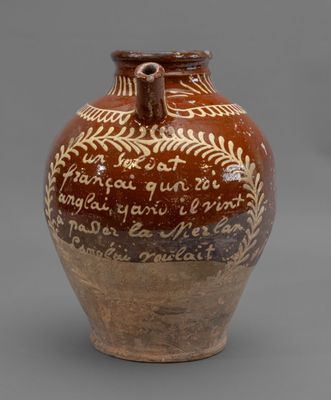 un vase marron et blanc, orné d'une inscription, posé sur une surface grise