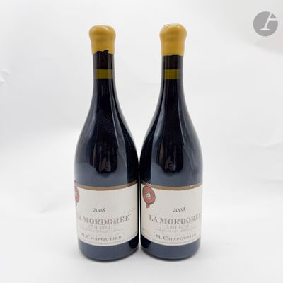 deux bouteilles de vin rouge posées l'une à côté de l'autre sur une surface blanche