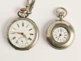deux montres de poche en argent posées l'une à côté de l'autre sur une surface blanche