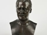 un buste en bronze représentant un homme moustachu sur fond blanc