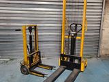 two forklifts sitting next to each other in front of a garage door