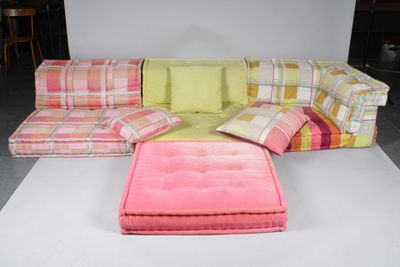 a couch and ottoman on the floor in front of a white backdrop