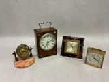 trois petites horloges et une petite horloge posées sur une surface blanche