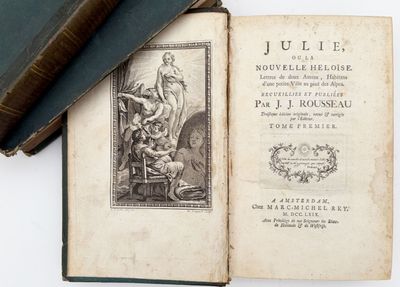 un livre ouvert posé sur une table à côté d'une pile de livres