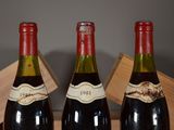 three bottles of wine sit in a wooden box on a table