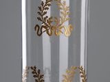 un vase en verre orné de motifs dorés, posé sur une table
