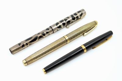 trois types de stylos différents sont alignés sur une surface blanche