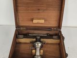 an old wooden box with a microscope in it on a white surface