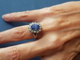 woman ' s hand with a diamond and sapphire ring on it ' s finger