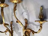 two gold wall sconces on a white wall