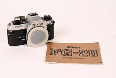 un petit appareil photo et une feuille de papier posée sur une surface blanche