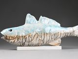 ceramic sculpture of a fish on a stand on a gray surface