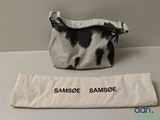 a black and white cow print bag next to a white bag