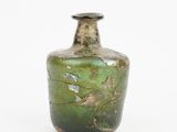 une bouteille en verre vert posée sur une surface blanche