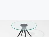 une table ronde en verre avec des pieds noirs et un plateau en verre