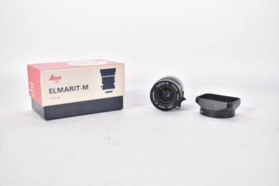 a close up of a camera lens and a box on a white surface