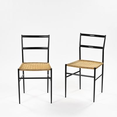 une paire de chaises noires avec des assises en osier sur fond blanc