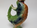 a figurine of a rooster on a green base