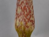 a red and yellow vase sitting on a white surface