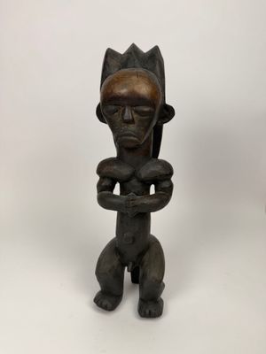 une petite statue en bois représentant un homme tenant un bébé dans ses bras