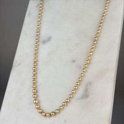 a gold beaded necklace on a marble stand