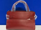 a red leather handbag with clear plastic handles on a table