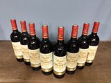six bottles of red wine are lined up on a wooden table