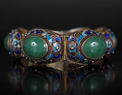 un gros plan sur un bracelet en or orné de pierres vertes et bleues
