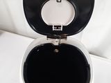 a white toilet with a black lid on a white sheet