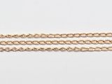 un gros plan d'un bracelet en or muni d'une chaîne, posé sur une surface blanche