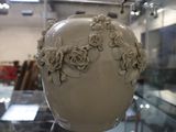 un vase blanc orné de fleurs, exposé dans une vitrine